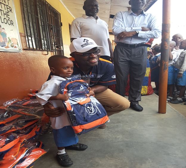 Sovereign Trust Insurance Plc, Segun Bankole poses with one of the Nursery Section recipients of school bags and exercise books